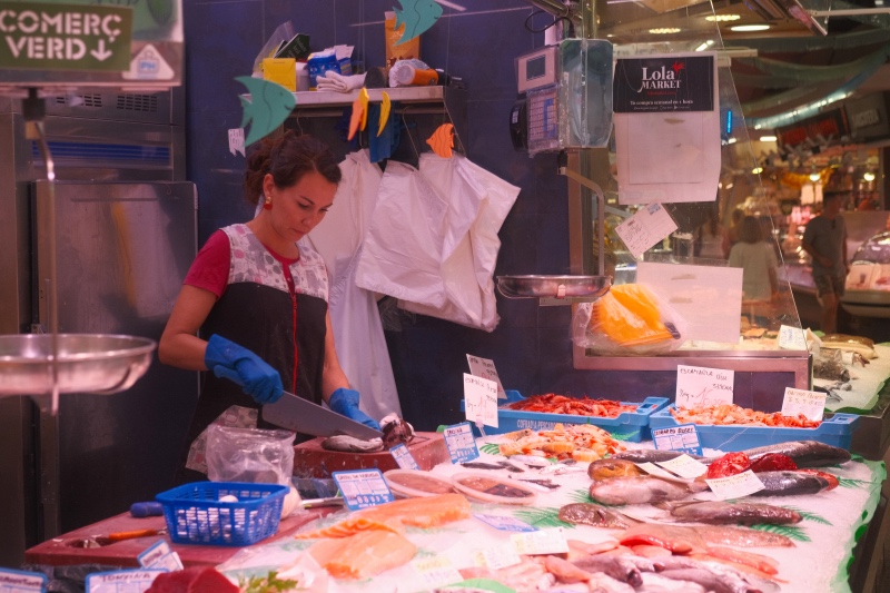 Fish merchant cutting fish for customers.