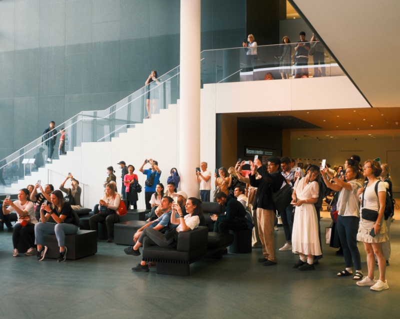 A crowd watches an interactive art exhibit in the main atrium of the MoMa, New York