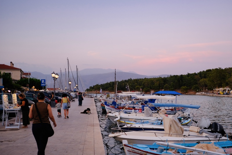 A picture taken in the harbor of Galaxidi, with boats and people, and the surrounding mountains in the distance.