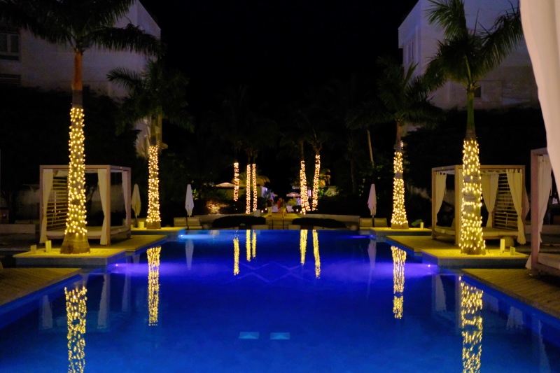 An outdoor pool, at night, with Christmas tree lights surrounding the pool in Turks and Caicos.