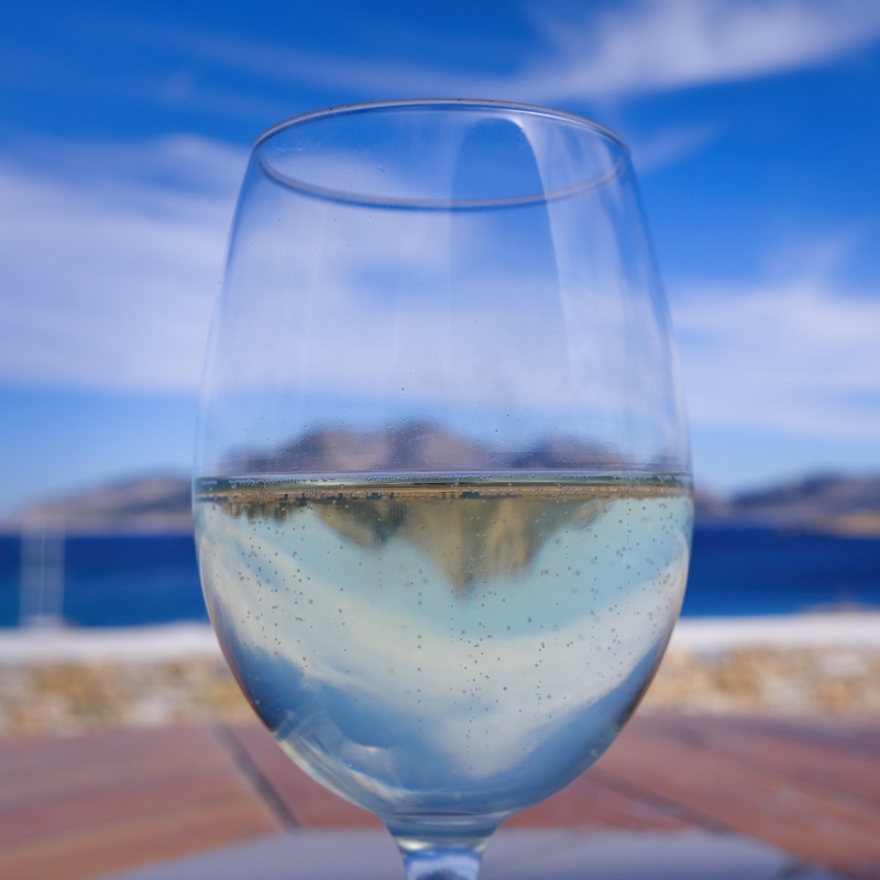 A closeup picture of a wine glass, with the Greek sea in the background.